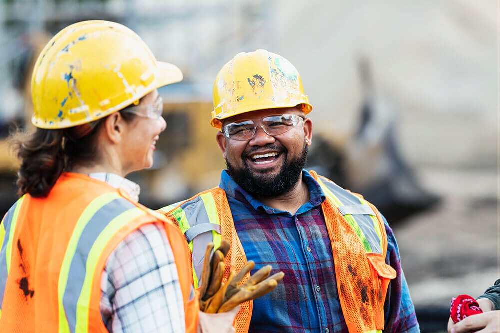 construction worker in hardhat laughing with coworker 